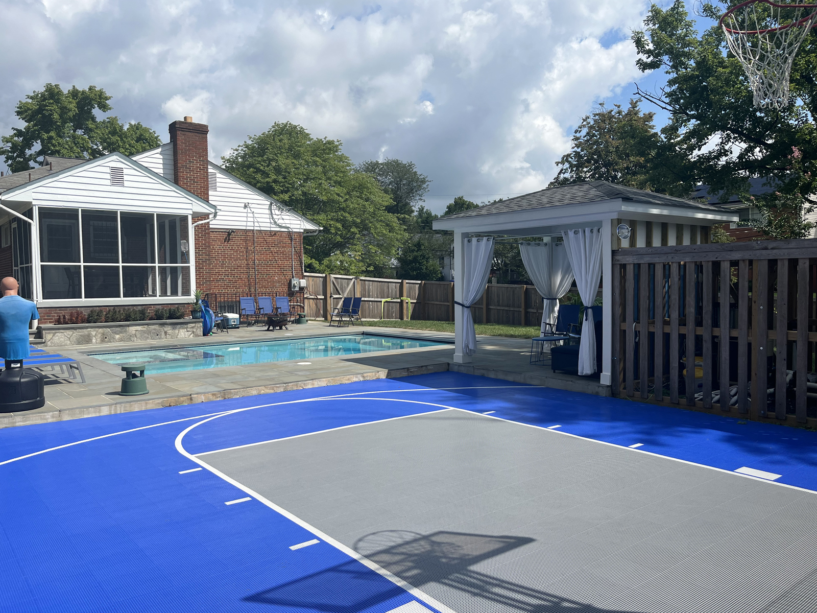 Blue and gray basketball half court in backyard with pool