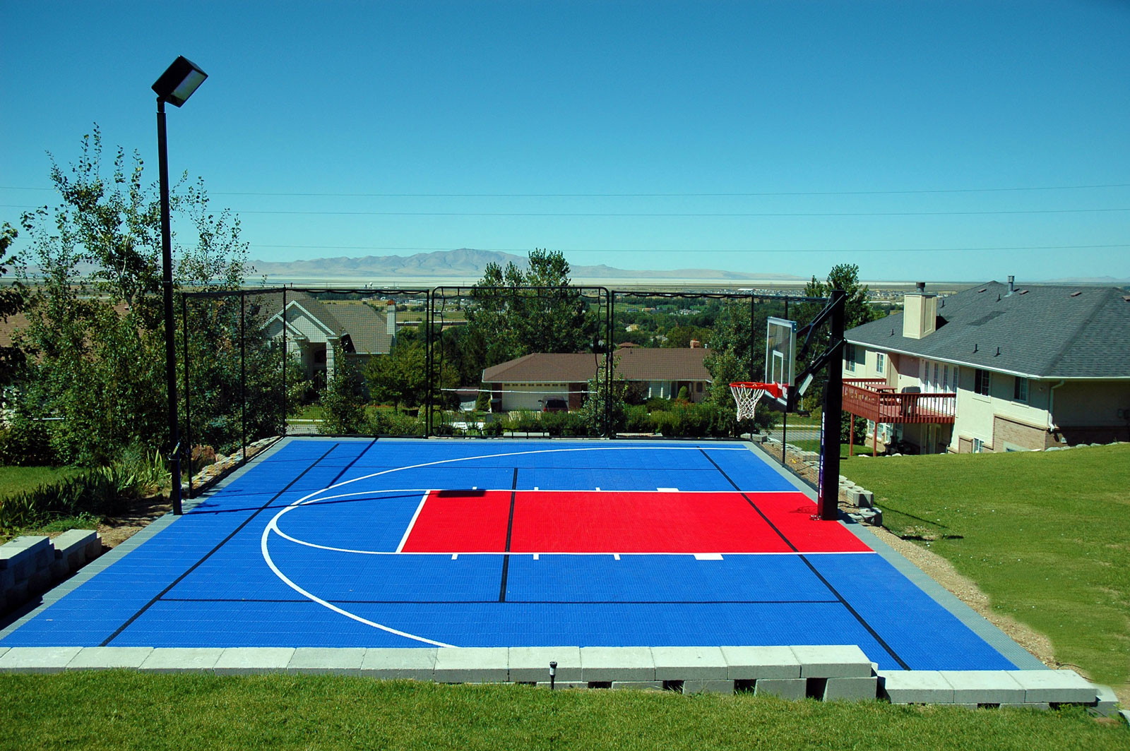 Multi-court in bright blue and red with lights and fencing