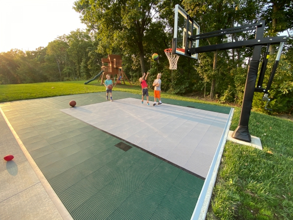 Kids playing basketball on an Evergreen and Gray basketball half court
