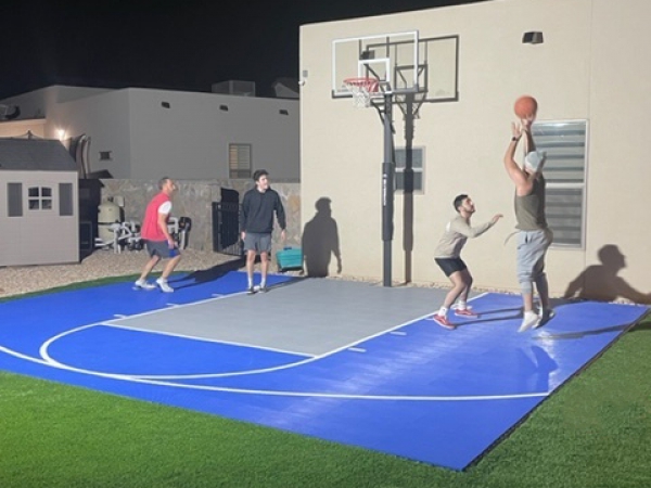 Men playing basketball at night on a Dunkstar backyard court