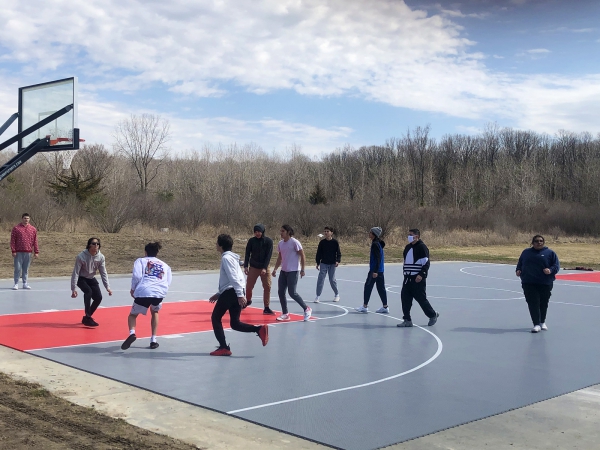 People playing on gray and bright red full basketball court