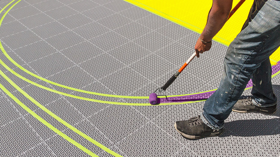 A man painting basketball lines on a court