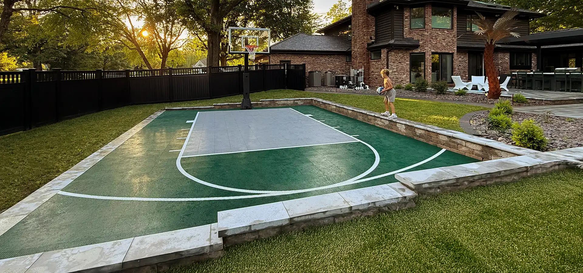 A young boy starting to play basketball on his new backyard basketball court.